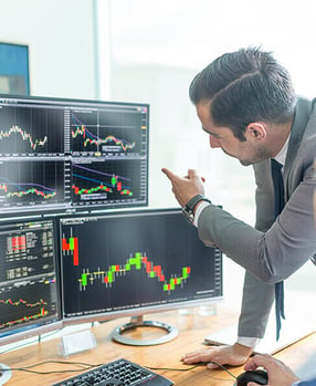 Man pointing at finance graphs on a computer screen