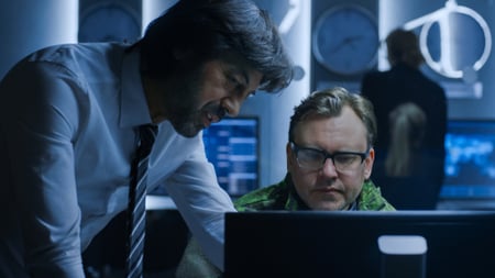 Image of two men looking at computer screen in office