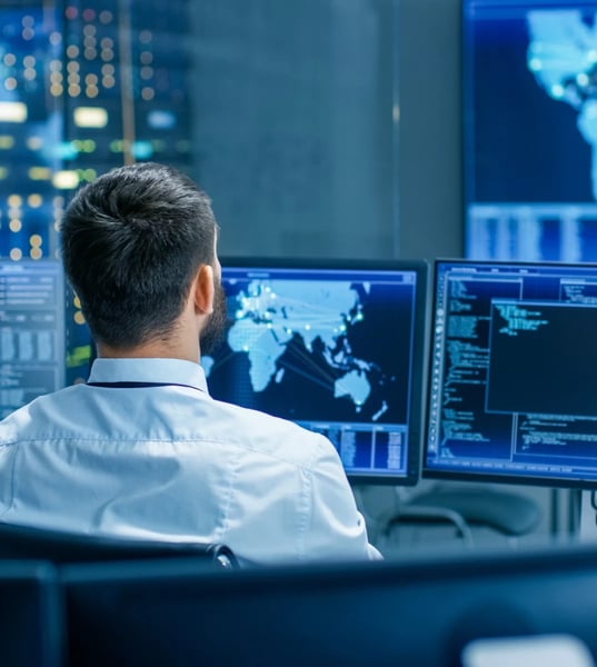 man sitting down looking at cyber security reports and screens