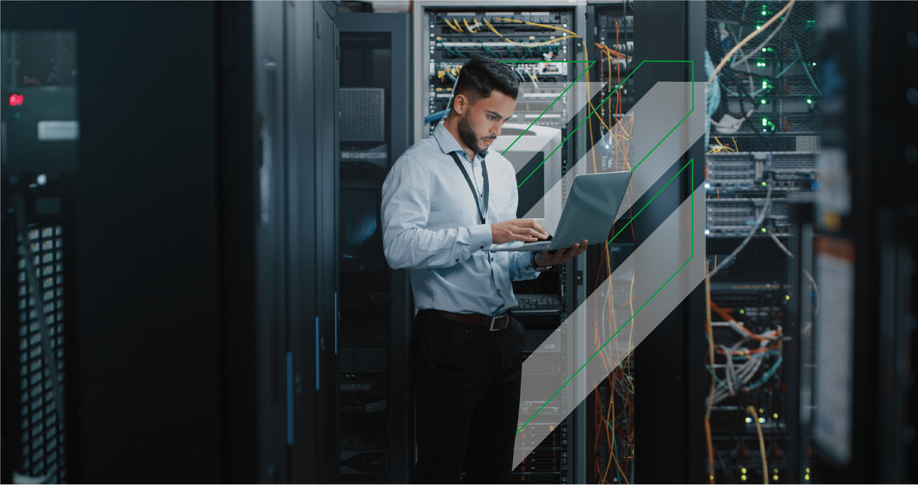 Male engineer using his laptop in a network server room.