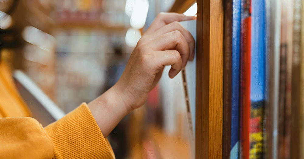 Close up of person choosing a book in a library.