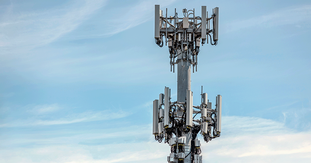 Close up of telecommunication mast in front of blue sky and scattered clouds.