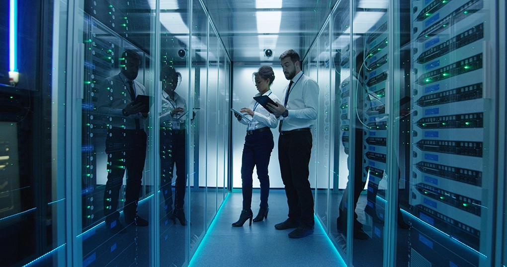 Two IT Technicians holding Ipads whilst checking servers in data center.