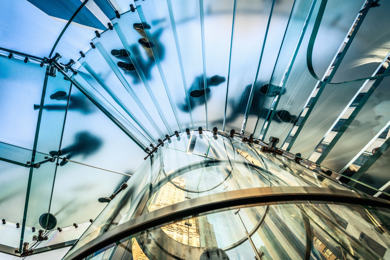 People walking on transparent glass staircase.